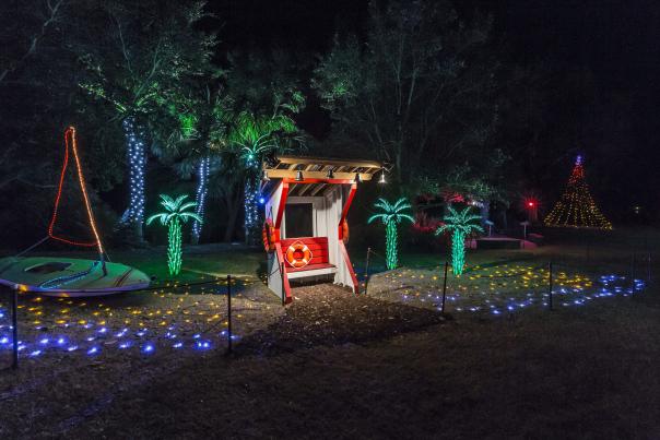 Enchanted Airlie light display with palm trees, a sail boat, and a life guard station