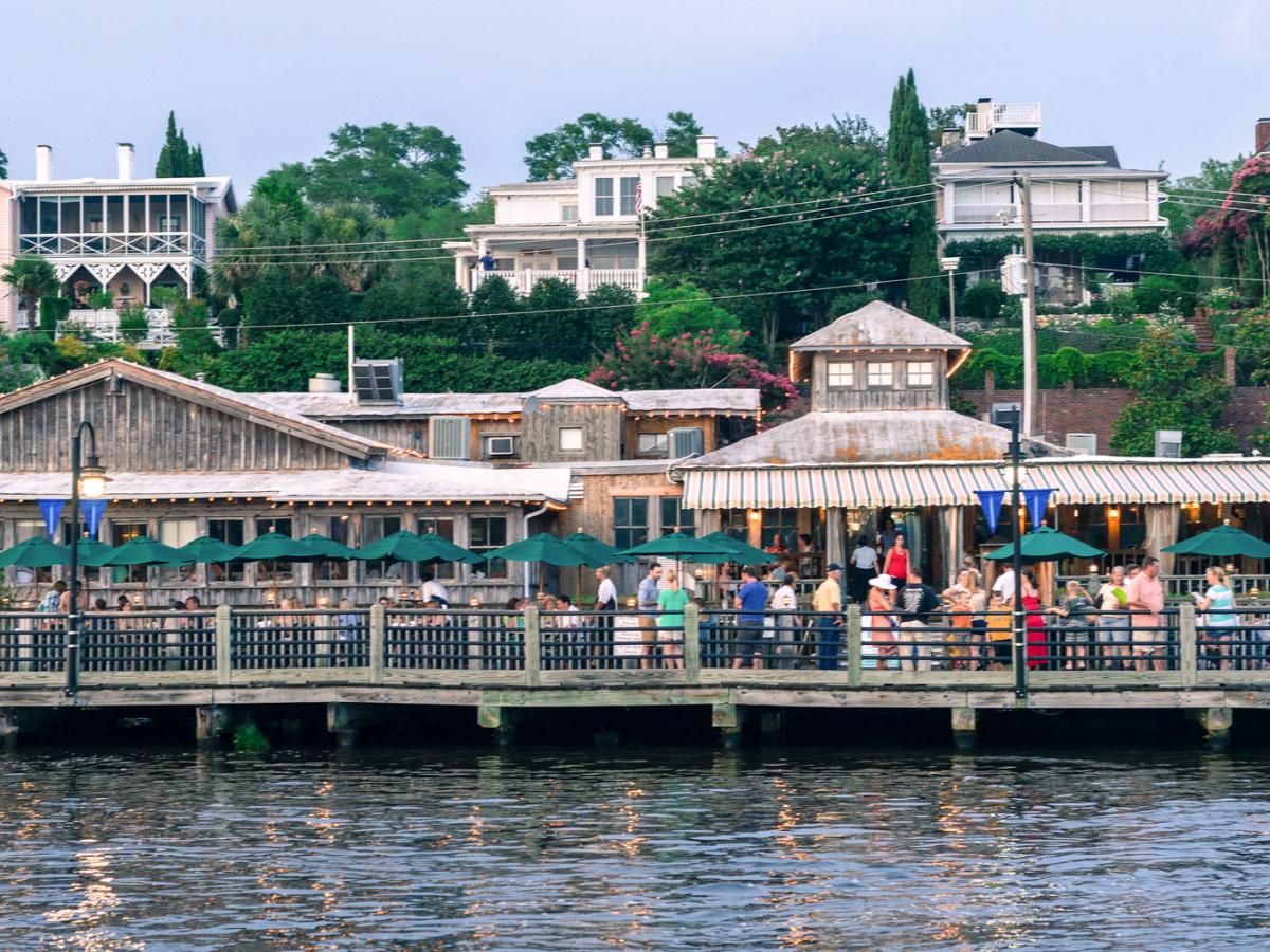 Shops and restaurants with patrons dining along the Wilmington Riverwalk